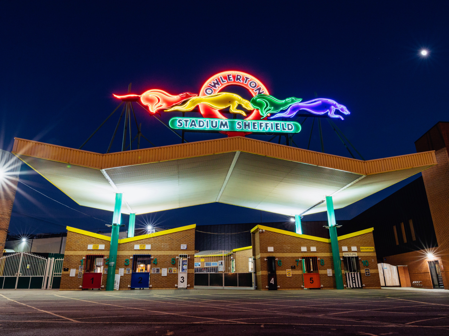 The neon sign above the entrance to Owlerton Stadium, depicting running greyhounds.