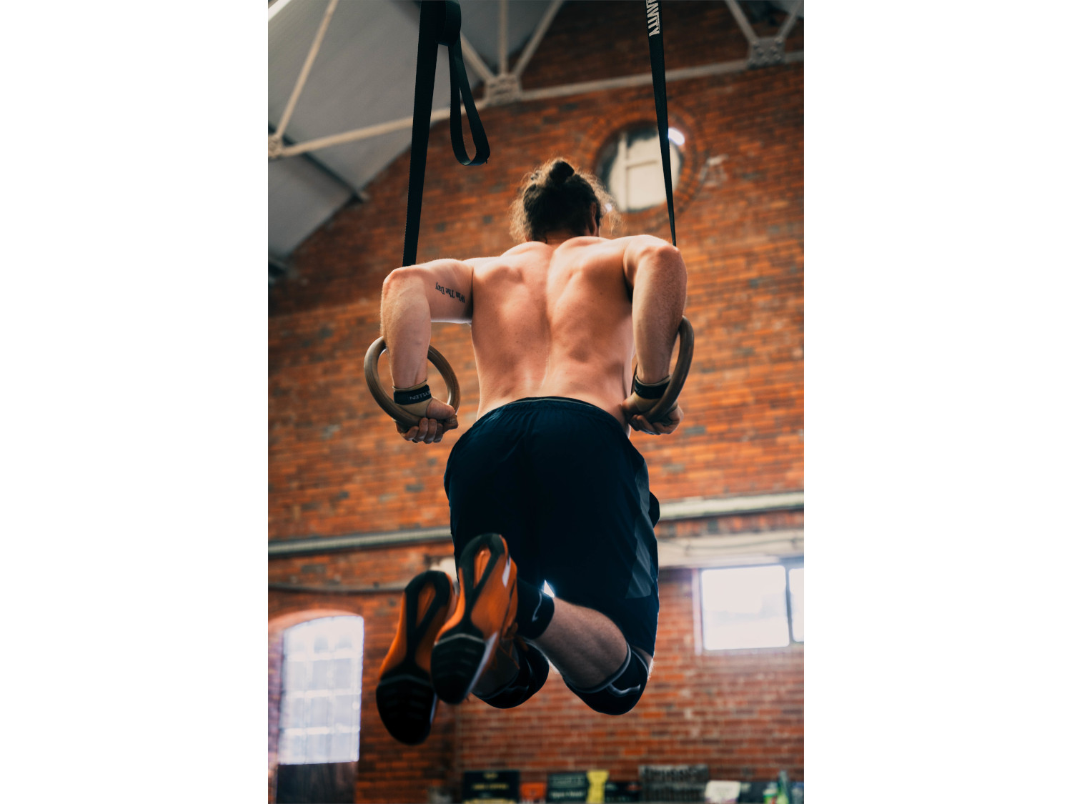 A man exercising on the rings at a gym.