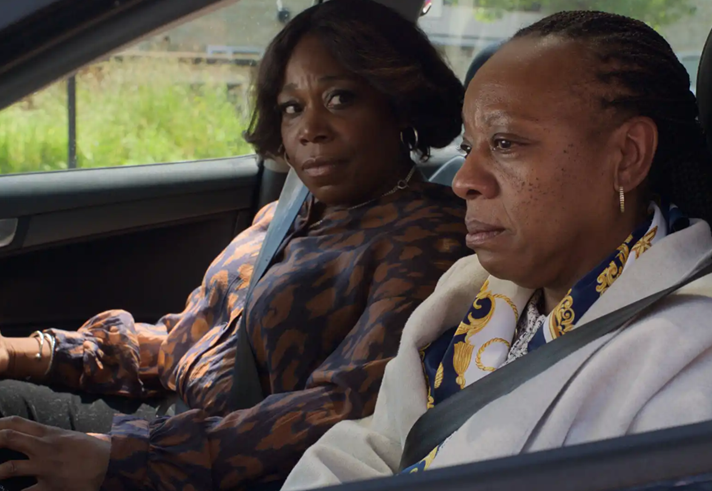 Two women of African heritage sitting in a car.
