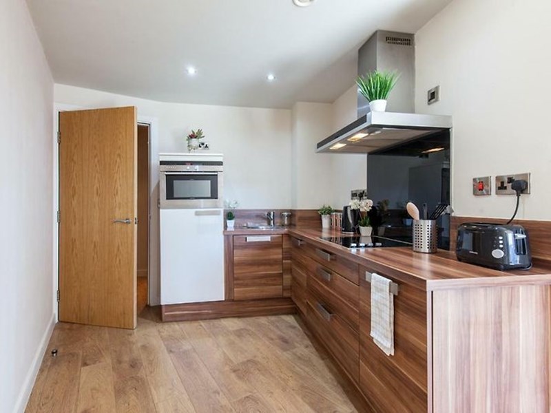 Compact kitchenette with essential appliances and storage cabinets.