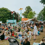 Families sit out on picnic blankets eating as other people queue for food from street food stalls at Tramlines festival
