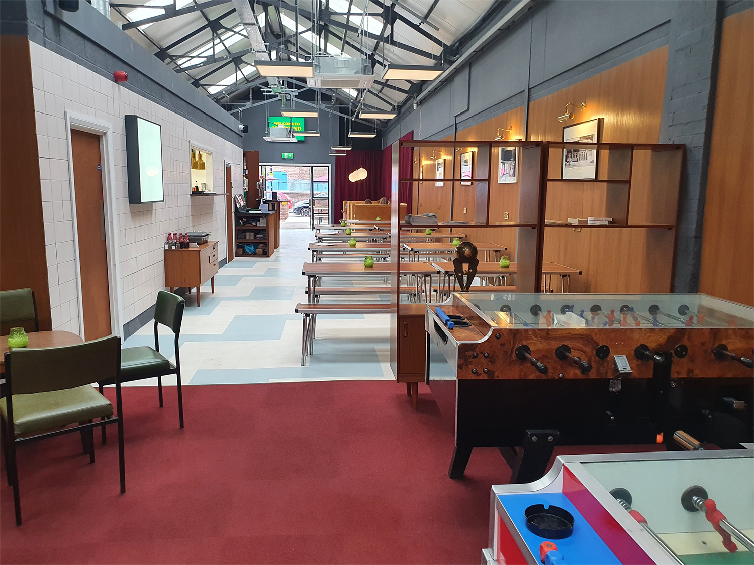 A photo looking down the length of Neepsend Social Club & Canteen with tables and chairs and Fussball tables