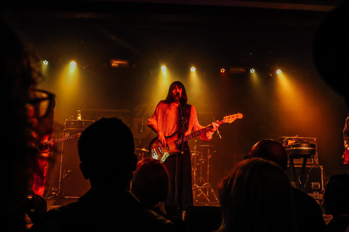 A band plays live on a darkly lit stage.