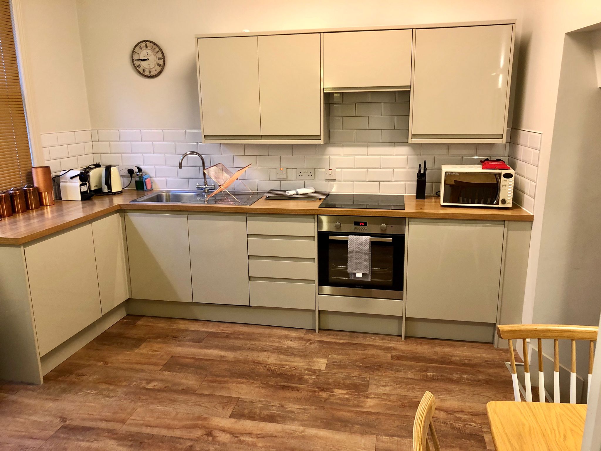 Small but functional kitchen at Homely Apartments – Figtree featuring stove, sink, and storage