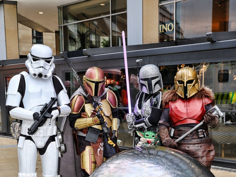 A group of people dressed in various storm trooper and Star Wars costumes pose in front of the steel ball sculptures in Sheffield City Centre