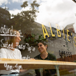 Two people sat in the window, drinking coffee, at Albie's Coffee.