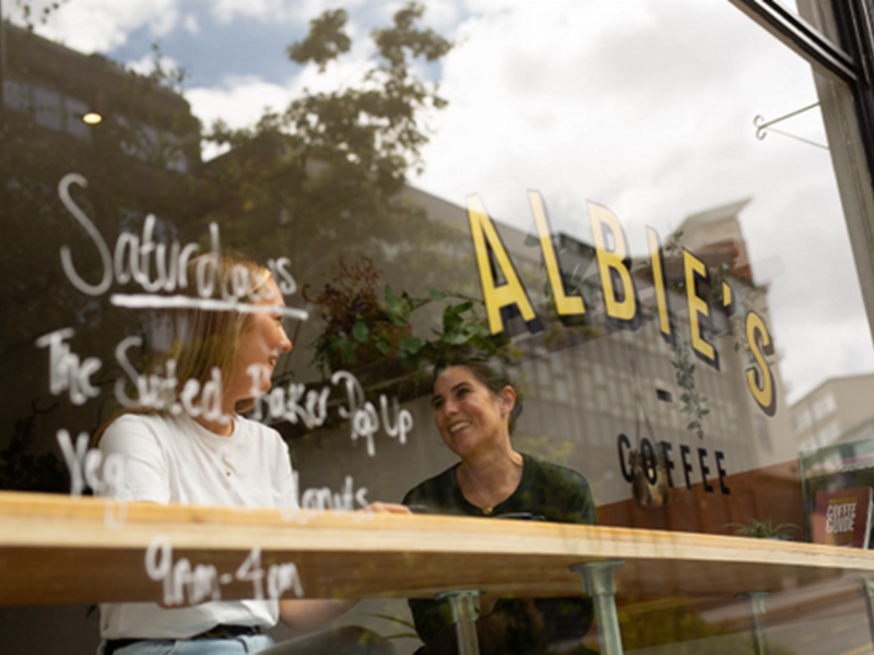 Two people sat in the window, drinking coffee, at Albie's Coffee.