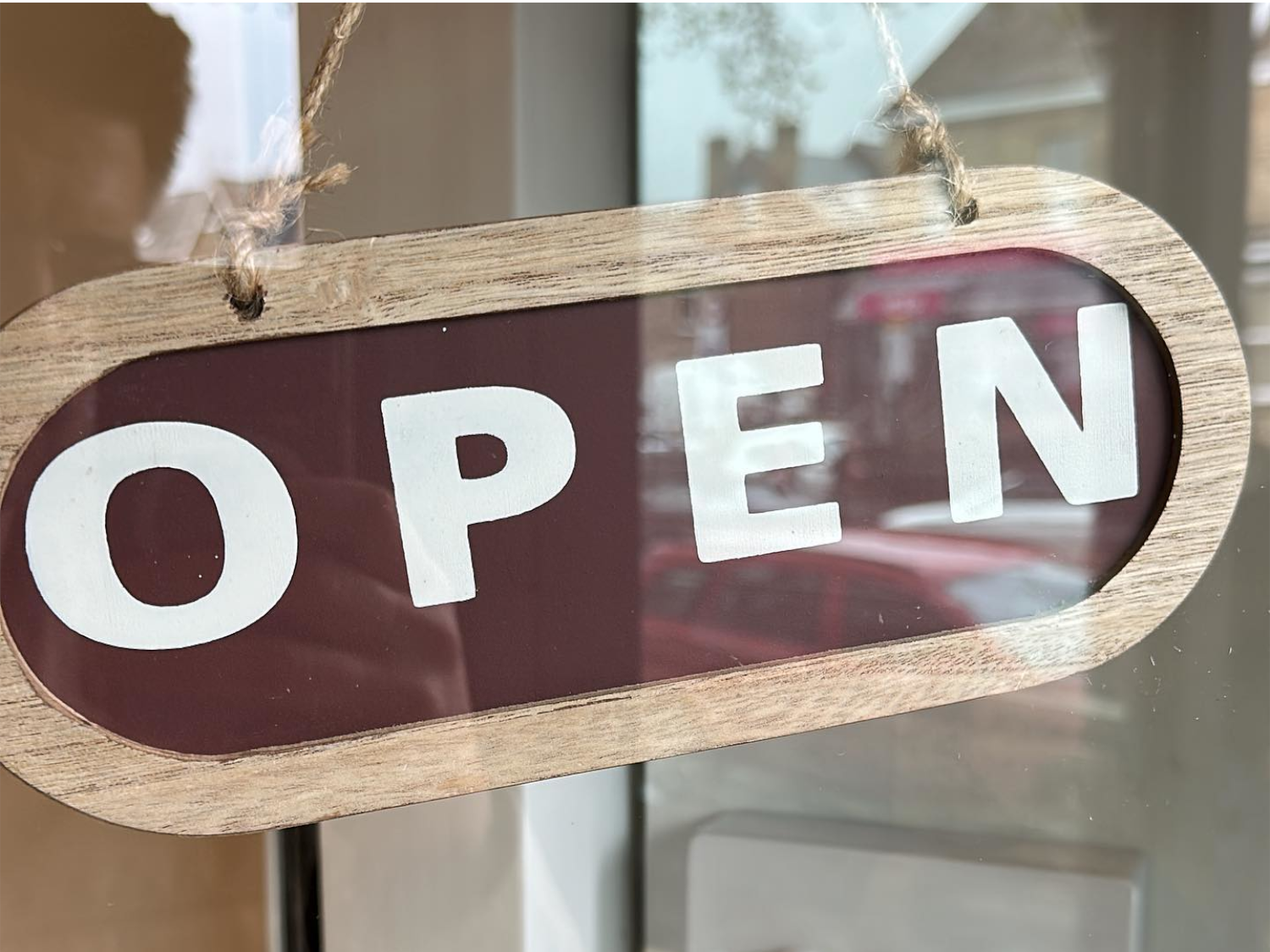 A wooden Open sign hanging in the door at Gills & Co.