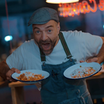 A chef holding two plates of food that are ready to go.