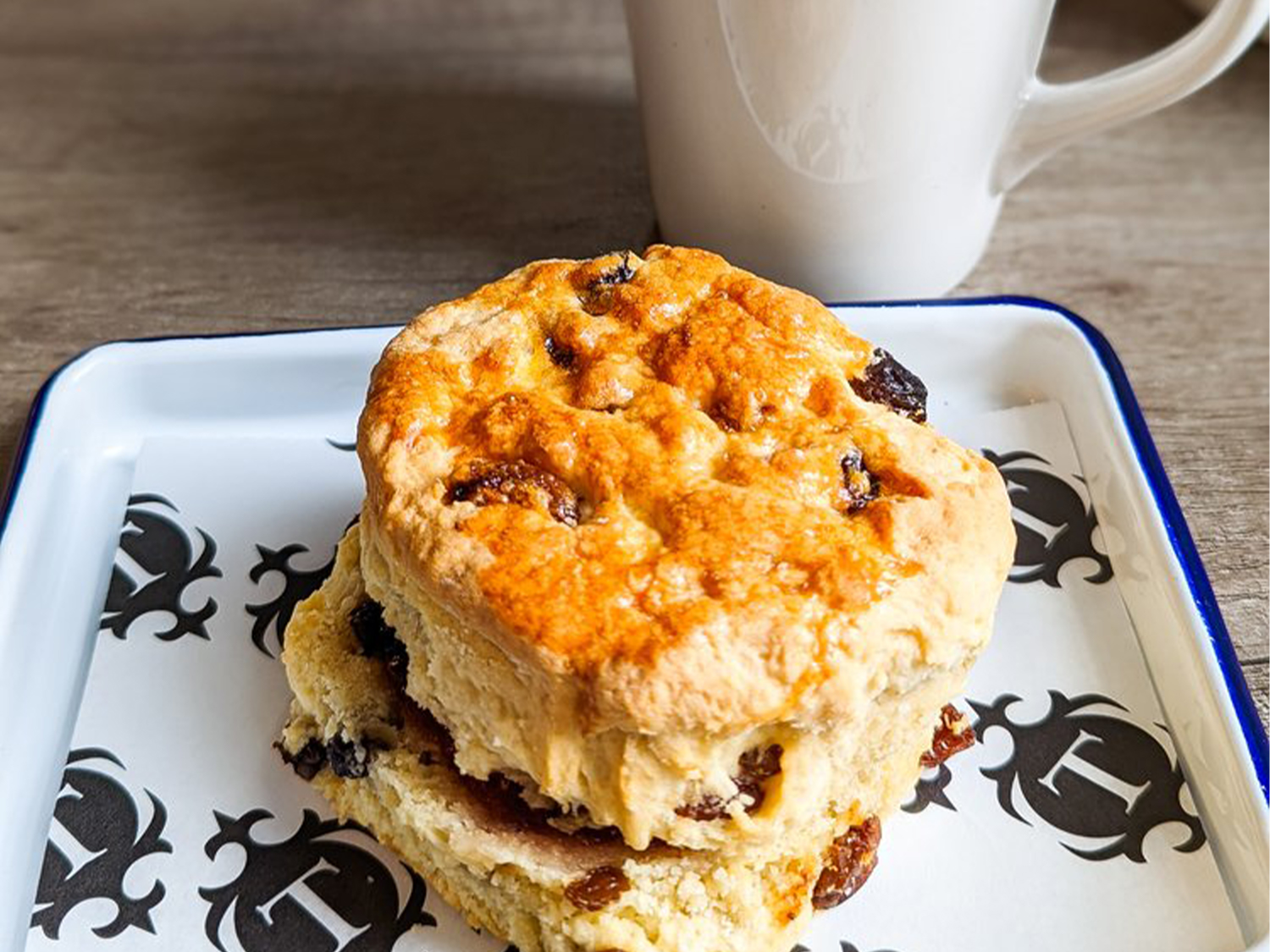 A scone on a plate with a mug of tea.