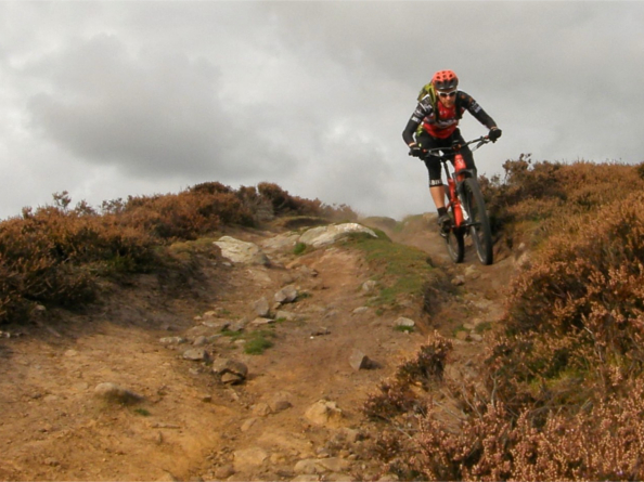 A person mountain biking up a steep hill in the countryside.