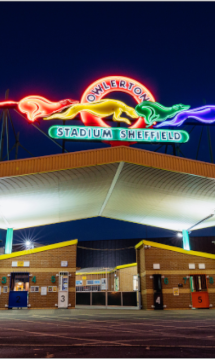 The neon sign above the entrance to Owlerton Stadium, depicting running greyhounds.
