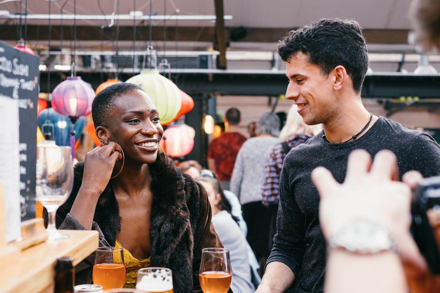 A woman and a man are sat chatting and having a drink in a bar.