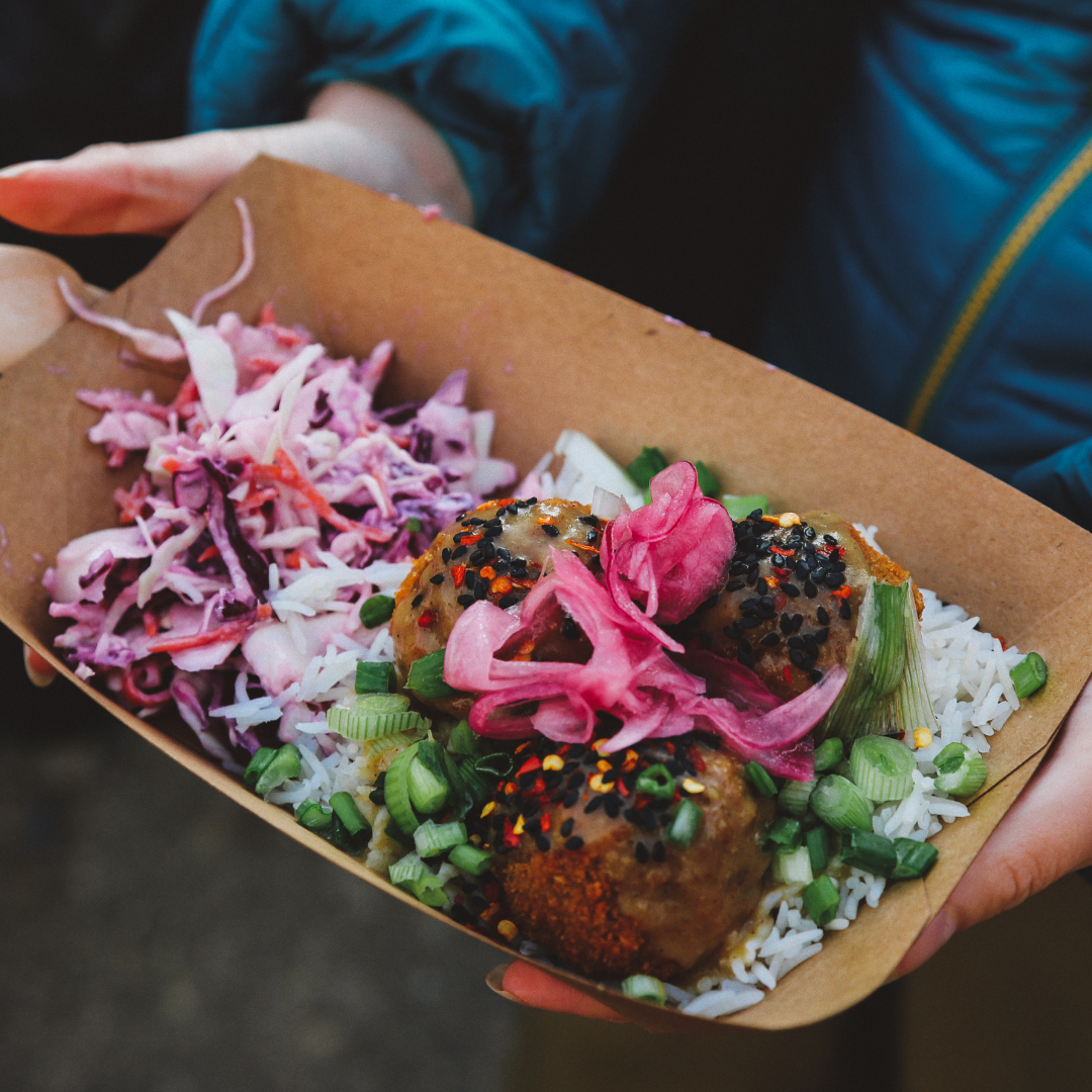 Someone holding at takeaway tray full of food.