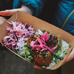 Someone holding at takeaway tray full of food.