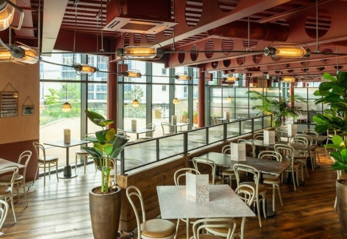 An interior shot of The Botanist showing it light an airy restaurant with tables and chairs and lots of planting.
