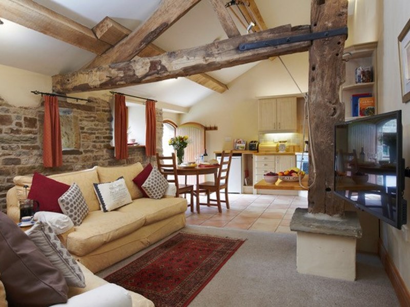 The living room in a small boutique hotel, with beams on the ceilings and stone walls.