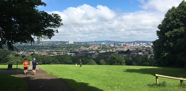Two people running in a park that overlooks Sheffield city centre.