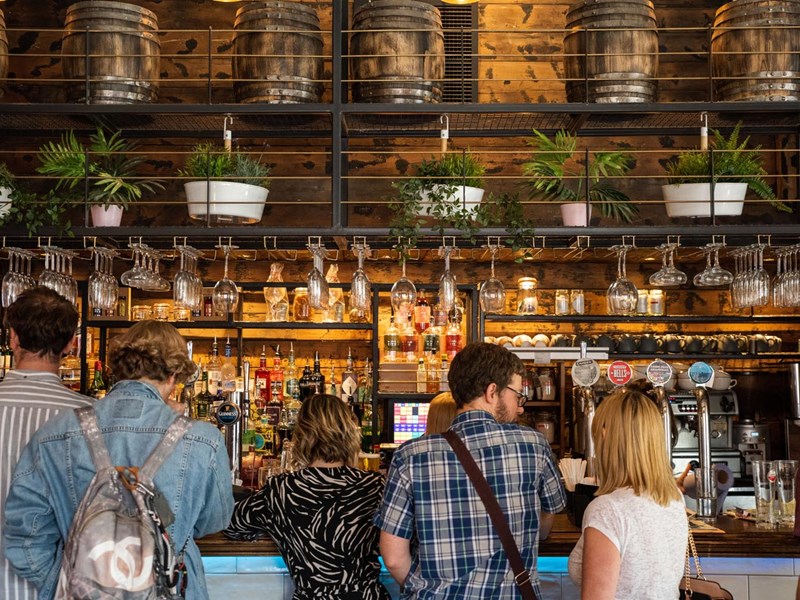 Six people standing at a bar.
