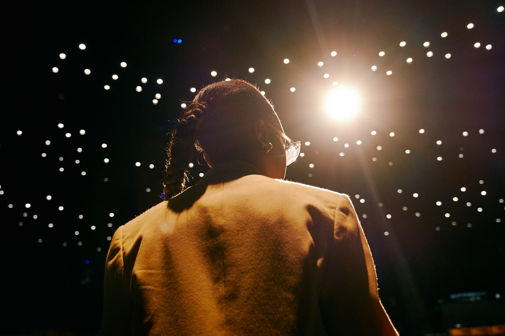 A woman delivers a presentation to a crowd in a darkened room.