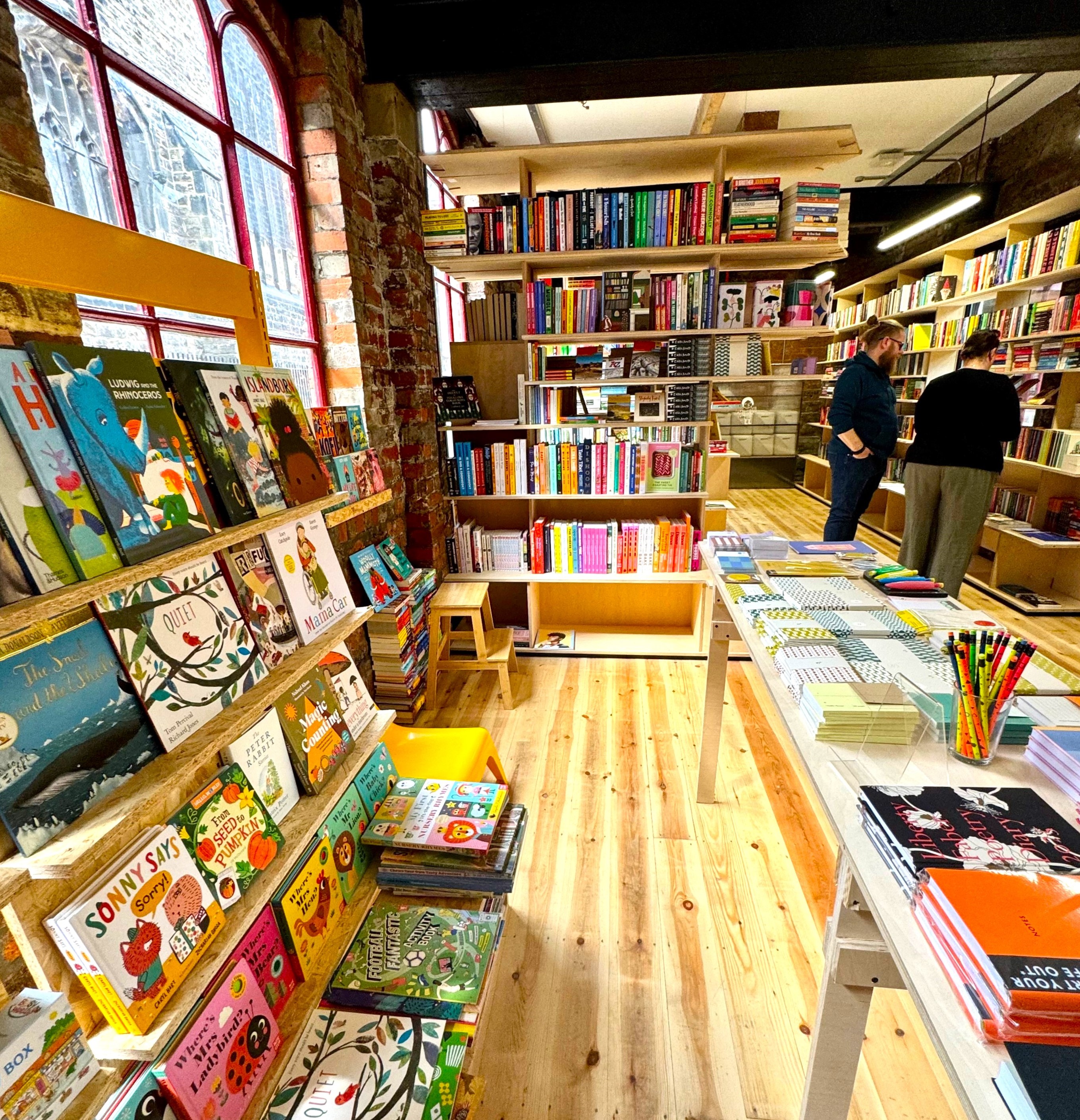 The interior of La Biblioteka bookshop, with all the walls lined with wooden shelves filled with books for sale.
