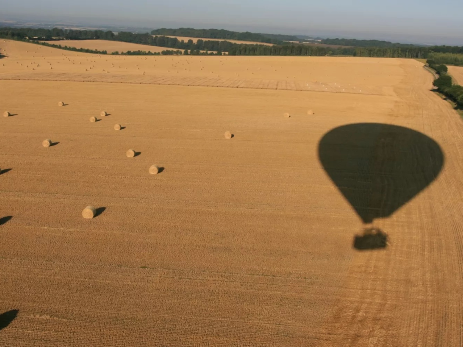 A hot air balloon flies over a scenic landscape.
