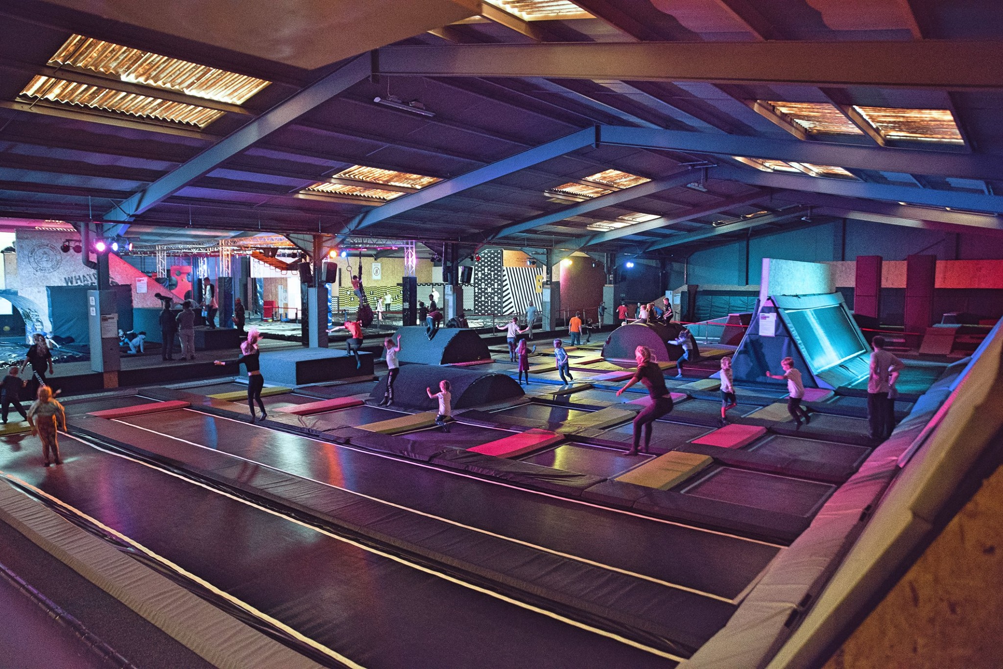 An interior shot of Jump Inc. with multiple trampolines and other play features. There are lots of people leaping about and having fun.