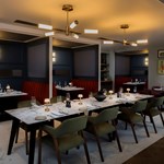 Restaurant with a set long table and chairs, with booths positioned behind.