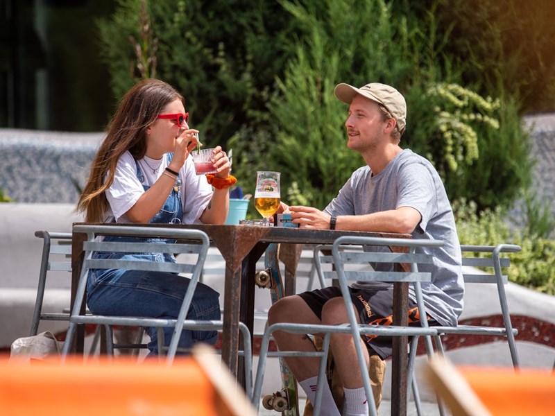 Two people having a drink in the outdoor seating area at Forum Kitchen + Bar.