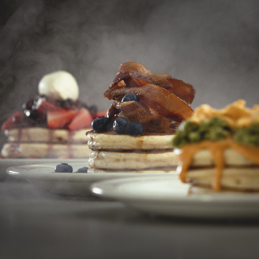 Three plates filled with stacks of pancakes.