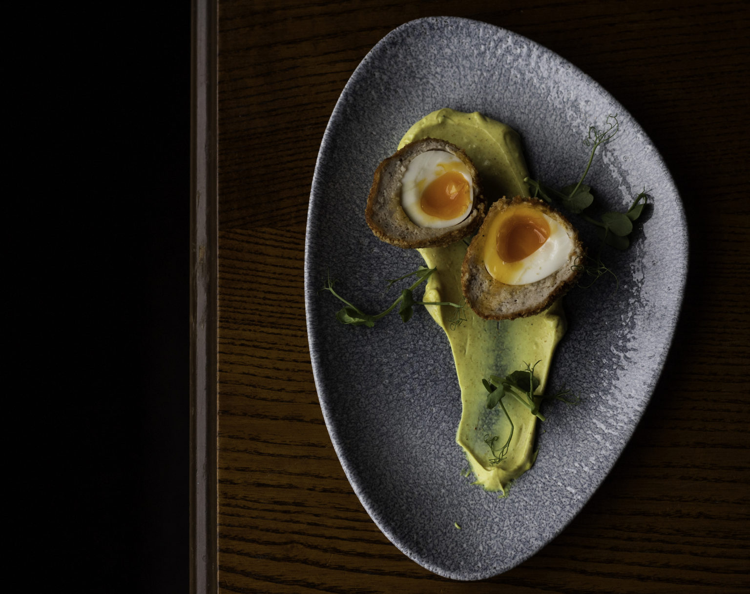 A plate with a scotch egg cut in two.