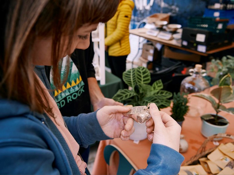Girl looking at tag of item on plant stall