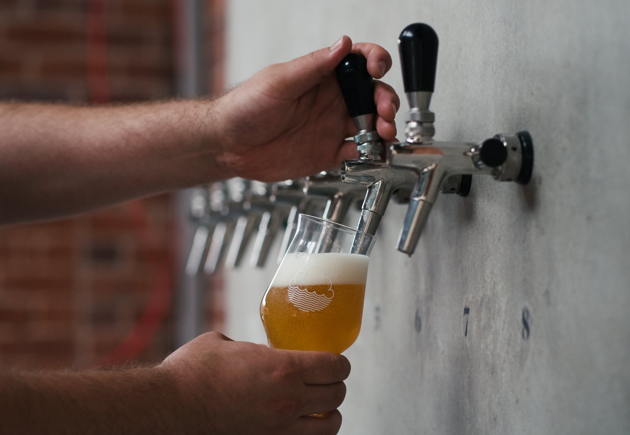 A pint being poured from pumps set into a wall.