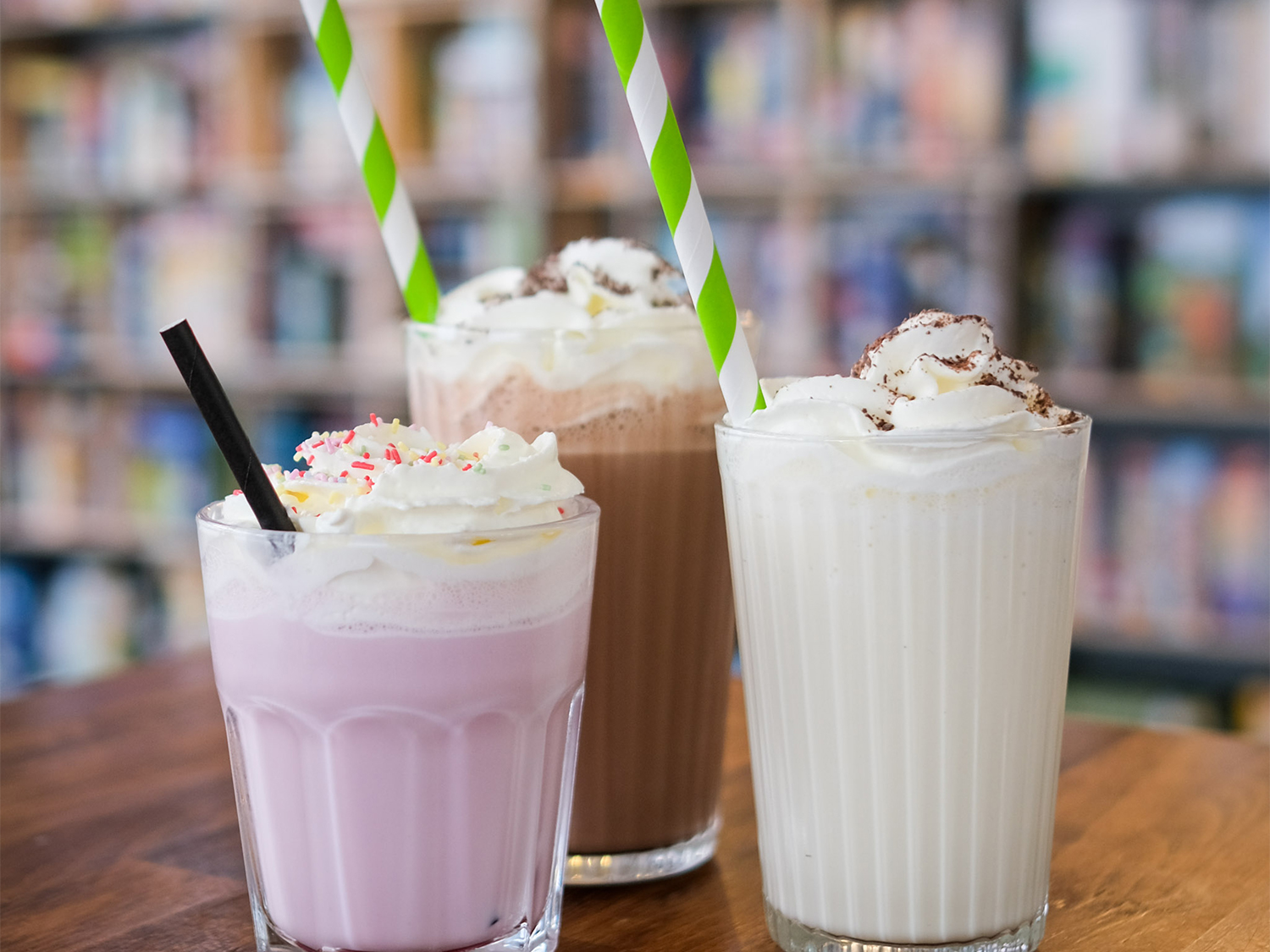 Three fancy milkshakes, with cream and sprinkles.
