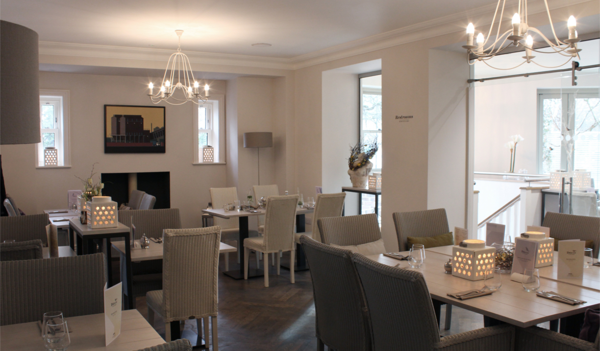 Restaurant and breakfast room with smart, modern set tables and cosy upholstered chairs.