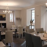 Restaurant and breakfast room with smart, modern set tables and cosy upholstered chairs.