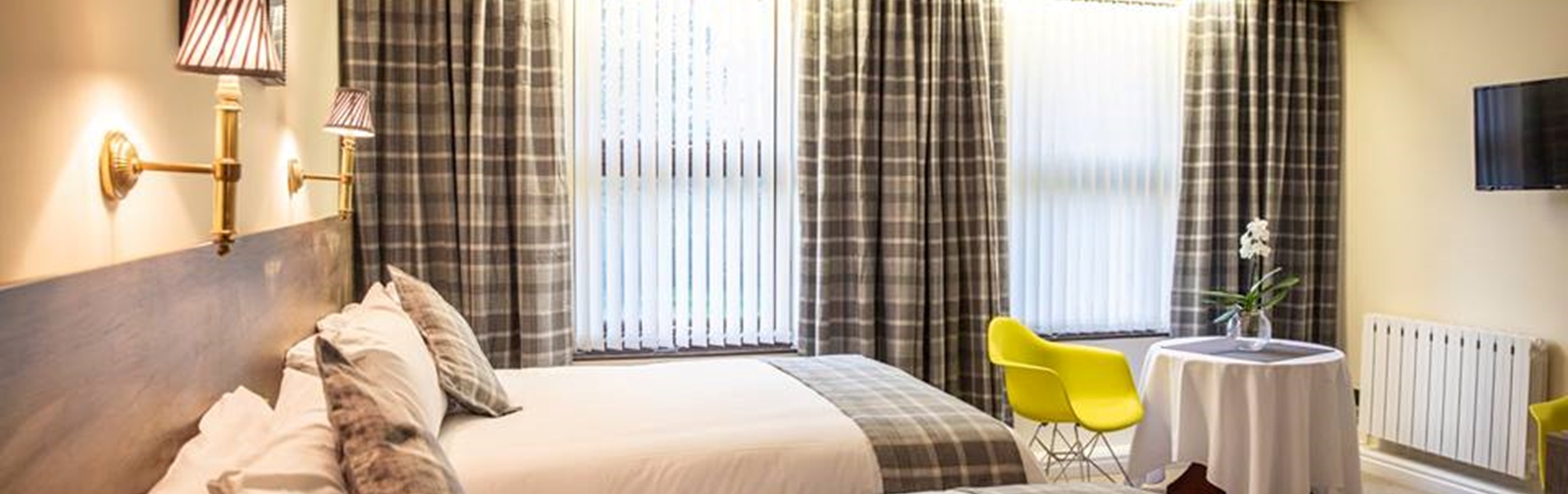 Hotel room with two double beds, beige furnishings, and a small table in the corner.