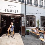 The courtyard at Tamper Coffee, with customers sat at tables.