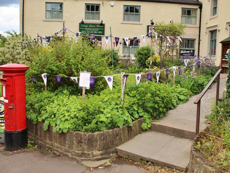 Wortley Cottage Guest House with stone walls, pitched roof, and garden area in front.