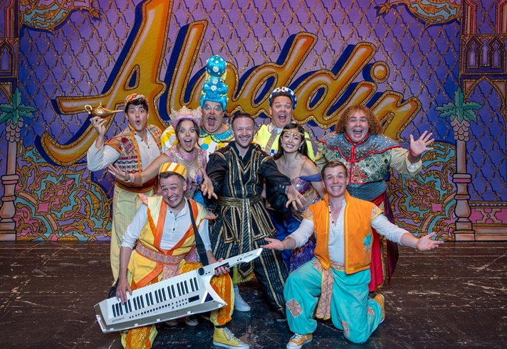 The cast of the Lyceum Panto Aladdin pose in a group shot with arms wide and joyful expressions
