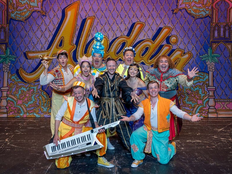 The cast of the Lyceum Panto Aladdin pose in a group shot with arms wide and joyful expressions