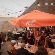 People eating outside at The Mowbray sat under large orange parasols.