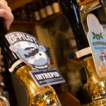 A hand pulling on a beer pump on a bar.