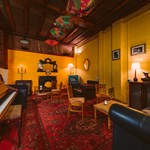 A room with a piano and a sofa and chairs around a low table.