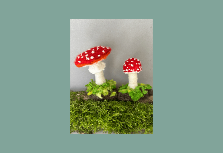 Two felted mushrooms on a log.