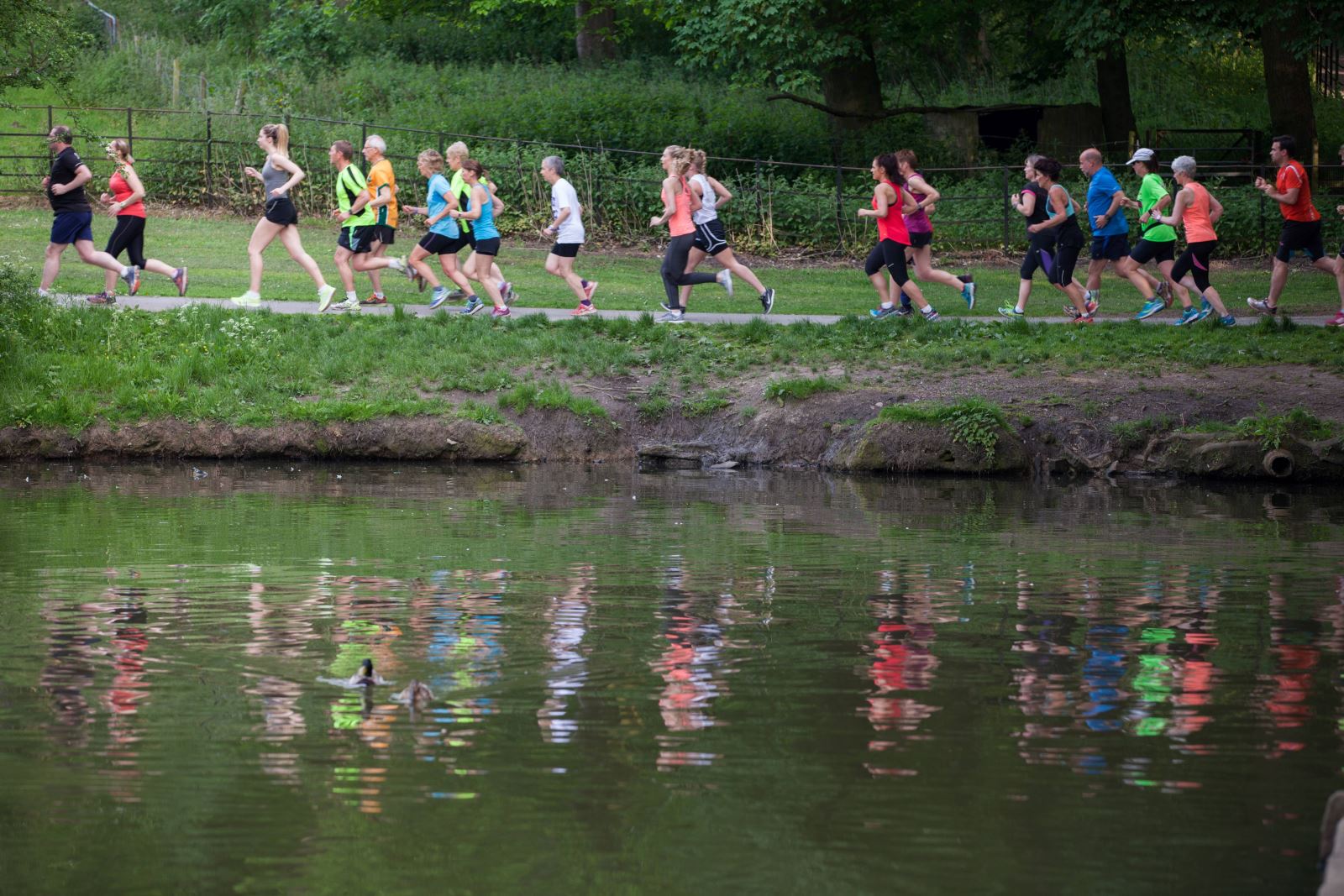 Group of runners participating in a park run alongside a lake.