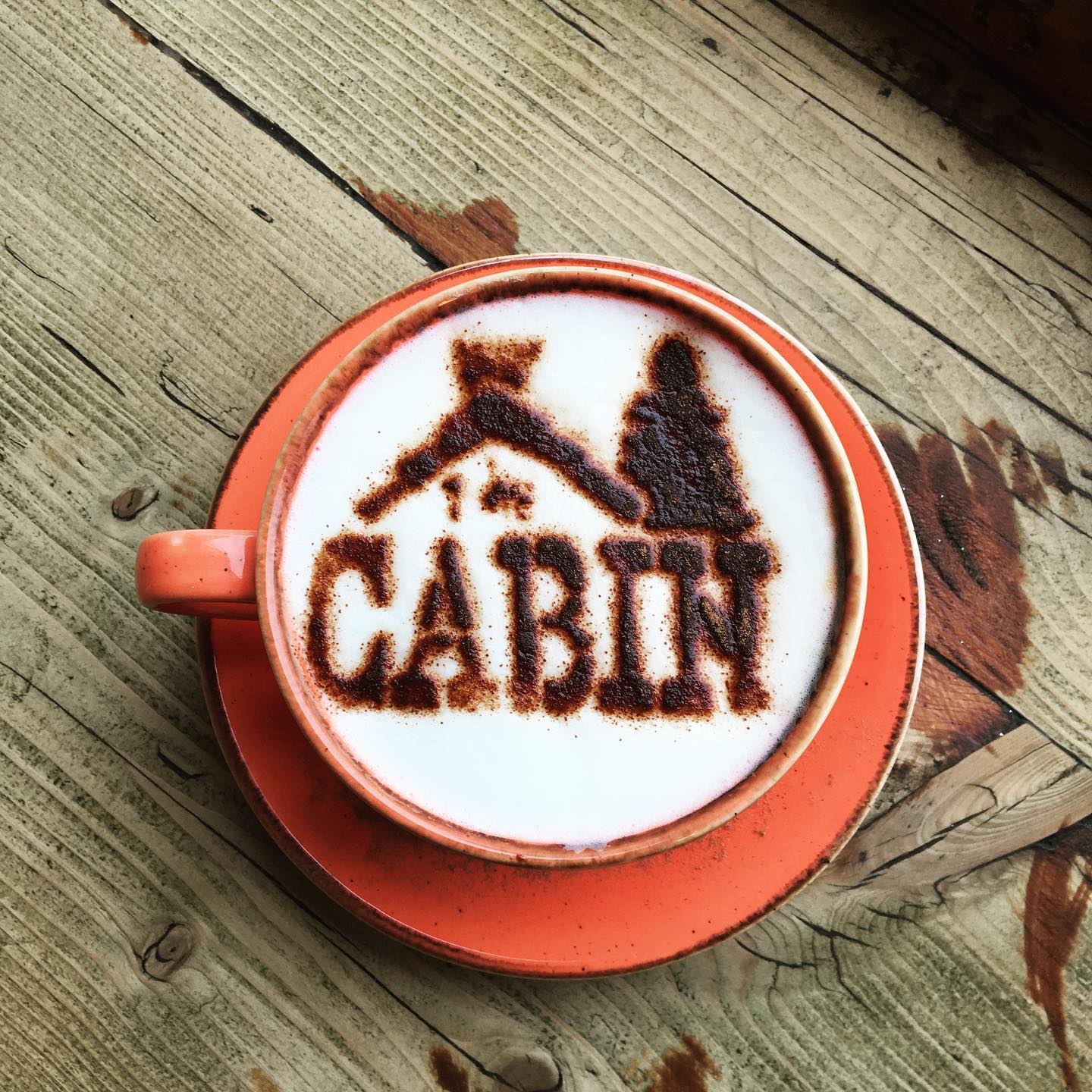 A cappuccino with The Cabin logo dusted onto the froth in chocolate powder.