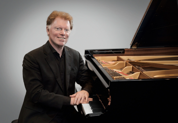 Tim Horton sat at a Grand Piano.