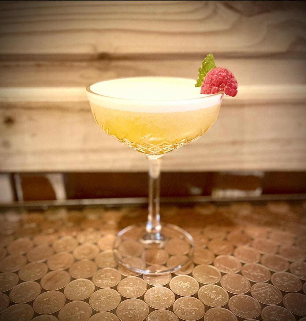 A yellow cocktail on a table.