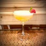 A yellow cocktail on a table.